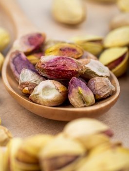 side-view-salted-roasted-pistachioson-wooden-spoon-old-paper-texture-background